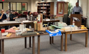 a group of people sitting at desks in a library surrounded by insulation and construction materials